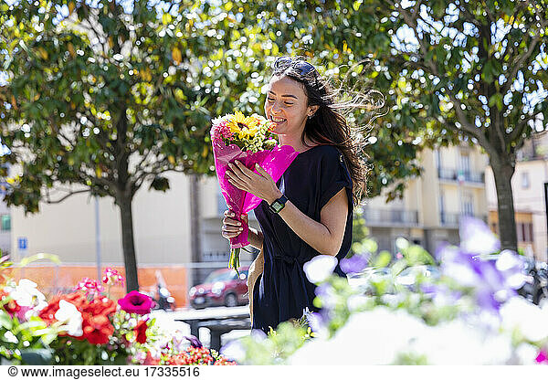 Smiling woman holding bouquet at flower shop