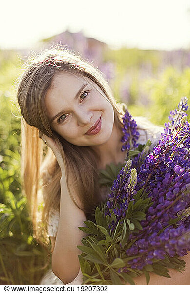 Smiling woman holding bunch of purple lupine flowers