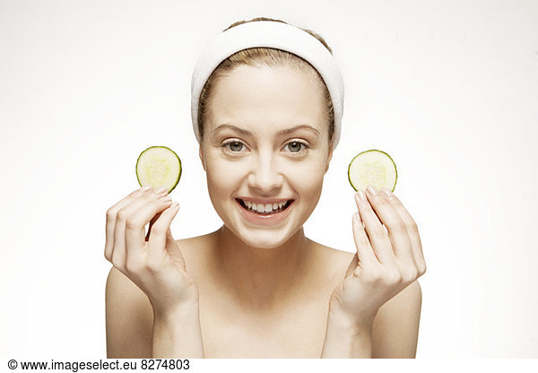 Smiling woman holding cucumber slices