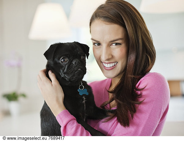 Smiling woman holding dog indoors