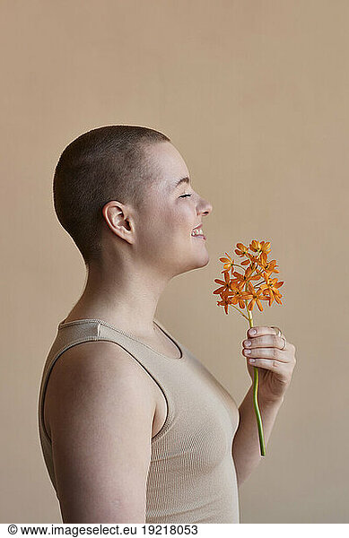 Smiling woman holding flower against beige background