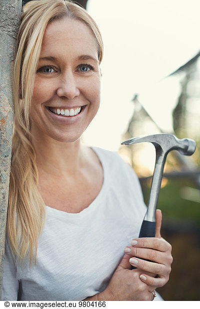 Smiling woman holding hammer while looking away