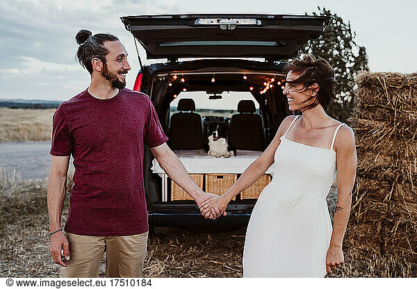 Smiling woman holding hands with man outside camper trailer