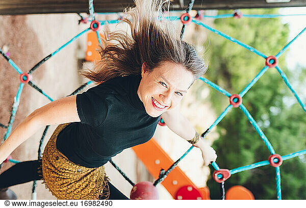 Smiling Woman Holding One Hand To A Net-Shaped Swing