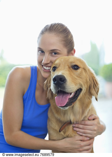 Smiling woman hugging dog indoors