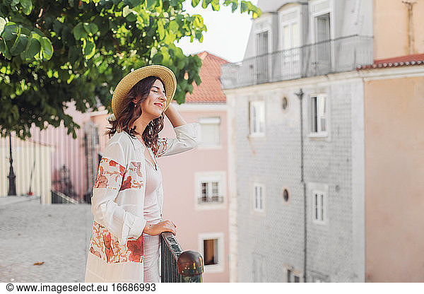 Smiling woman in a straw hat with eyes closed in Lisbon  Portugal