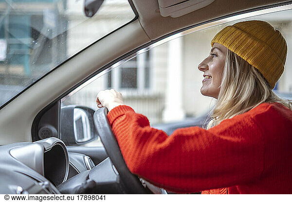 Smiling woman in knit hat driving car
