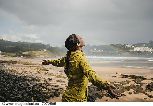 Smiling woman in raincoat at beach during rainy season
