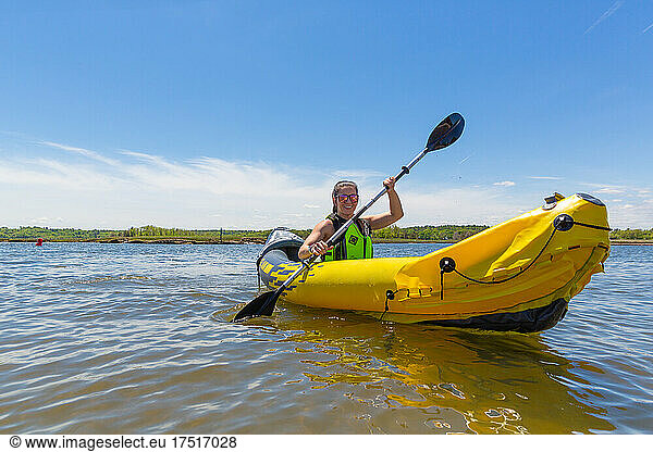 Smiling Woman in Yellow Kayak on the Water in New England