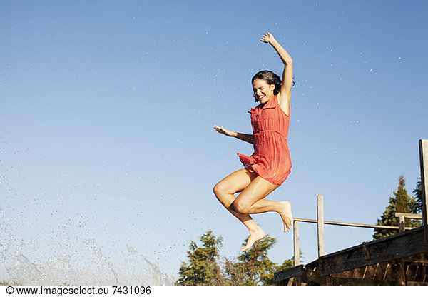 Smiling woman jumping off dock