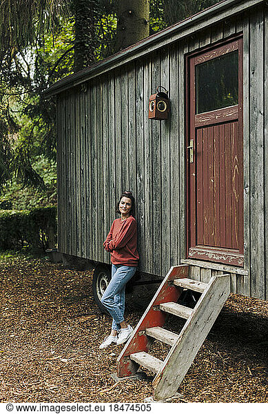 Smiling woman leaning on wooden cabin
