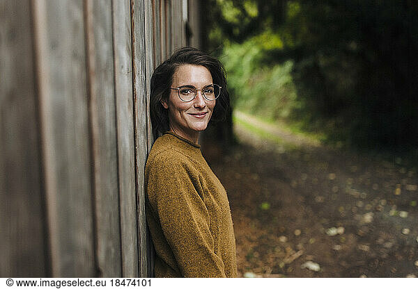 Smiling woman leaning on wooden wall