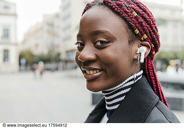 Smiling woman listening music on wireless in-ear headphones
