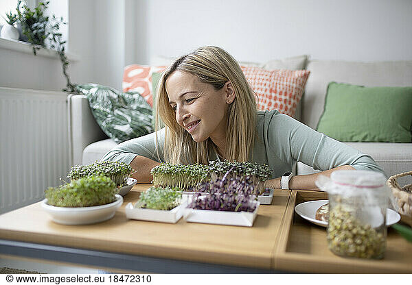 Smiling woman looking at homegrown saplings at home