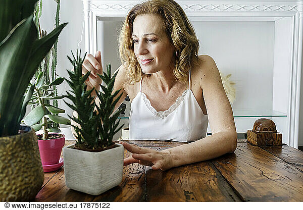 Smiling woman looking at houseplants at home