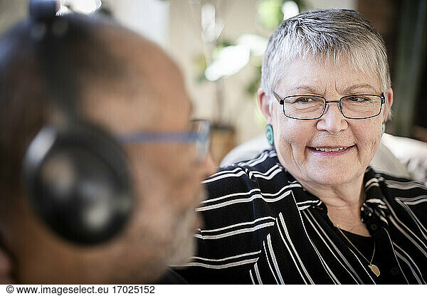 Smiling woman looking at man with headphones at home