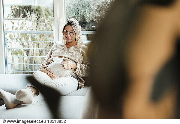 Smiling woman looking at ultrasound photo at home