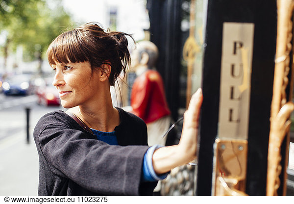 Smiling woman looking away while standing outside restaurant