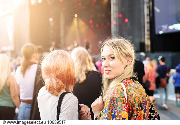 Smiling woman looking away while standing with friend at music festival