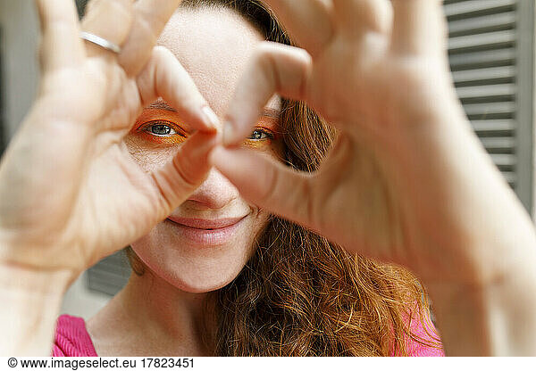 Smiling woman looking through binoculars made from fingers