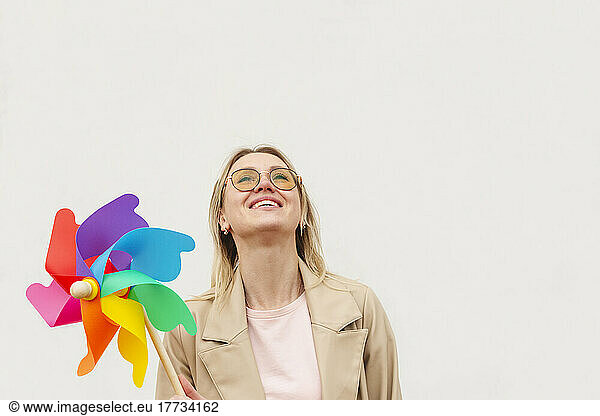 Smiling woman looking up holding colorful pinwheel toy against white background