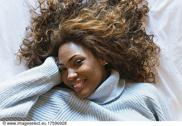Smiling woman lying on bed in bedroom