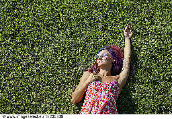 Smiling woman lying on grass enjoying sunny day