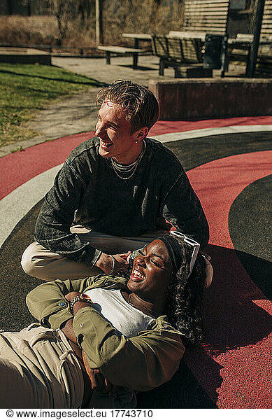 Smiling woman lying on lap of male friend relaxing in playground