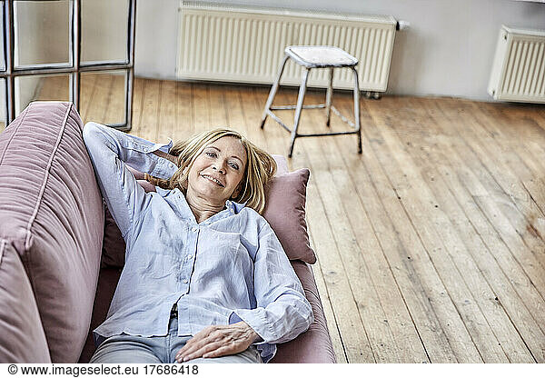Smiling woman lying on sofa at home