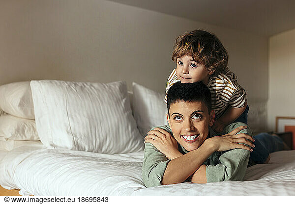 Smiling woman lying with son on bed at home