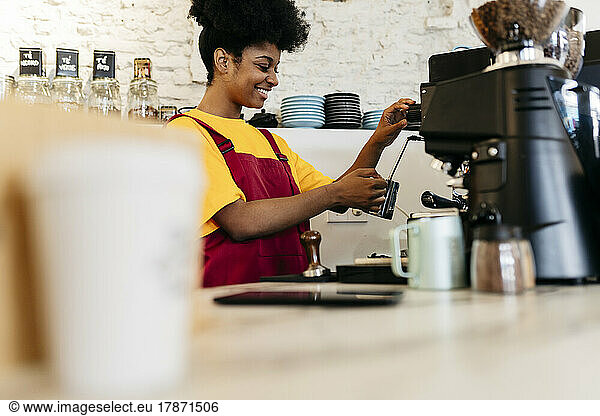 Smiling woman making coffee in cafe