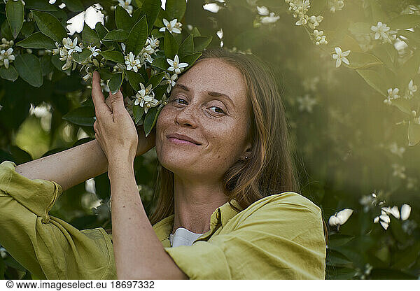 Smiling woman near blooming tree in garden