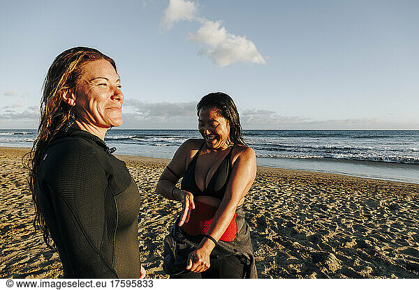 Smiling woman near surfer removing wetsuit at beach  Gran Canaria  Canary Islands