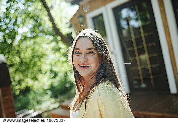 Smiling woman on porch in front of house