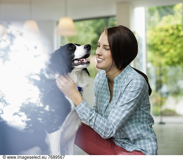 Smiling woman petting dog indoors