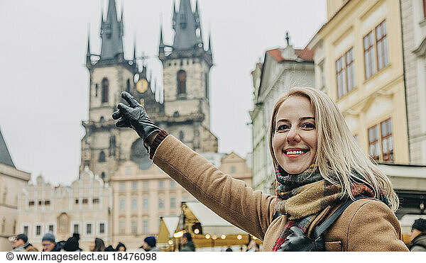 Smiling woman pointing at building in city