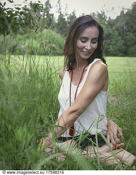 Smiling woman practicing yoga on grass in nature