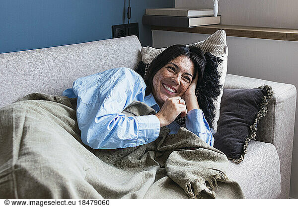Smiling woman relaxing on sofa in living room