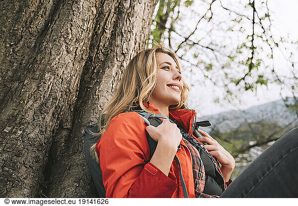 Smiling woman resting near tree