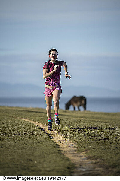 Smiling woman running on footpath
