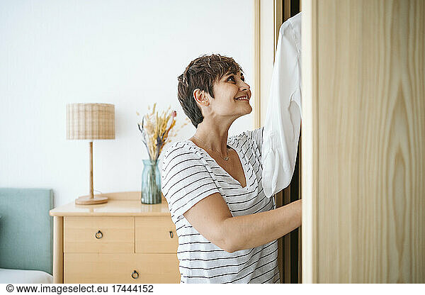 Smiling woman searching for clothes in closet