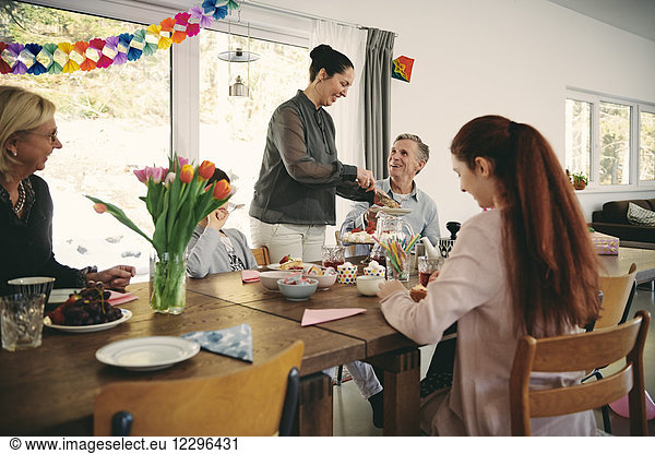Smiling woman serving food to family during birthday party