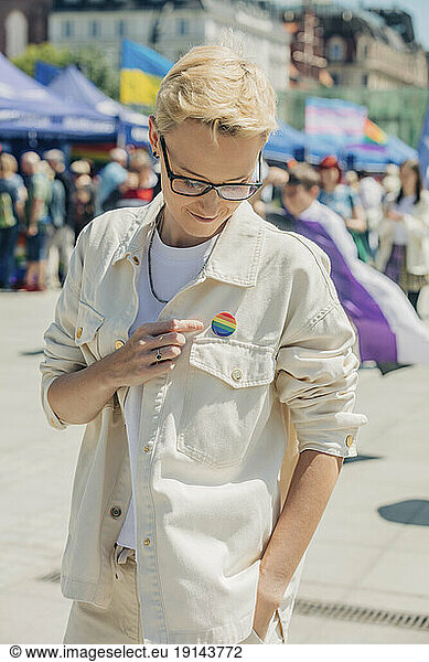 Smiling woman showing rainbow badge at gay pride event