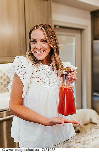 Smiling woman shows off her freshly made carafe of homemade juce