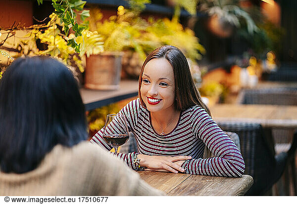 Smiling woman sitting in fany retsautrant  talking to friend