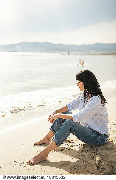 Smiling woman sitting on sand at beach