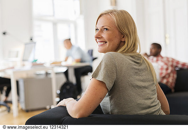 Smiling woman sitting on sofa in office