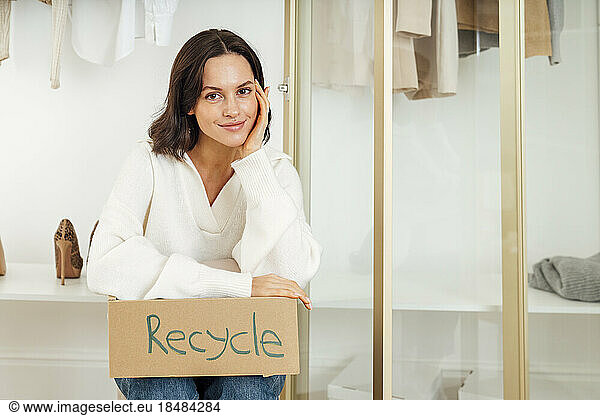 Smiling woman sitting with box of recycle at home
