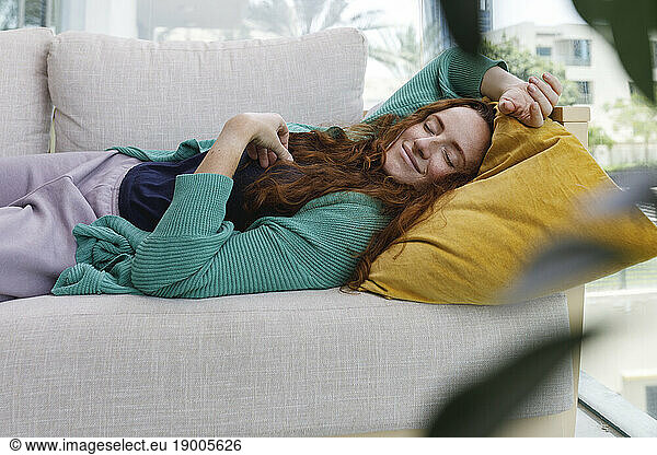 Smiling woman sleeping on sofa at home