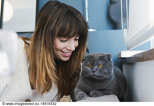 Smiling woman spending leisure time with cat at home